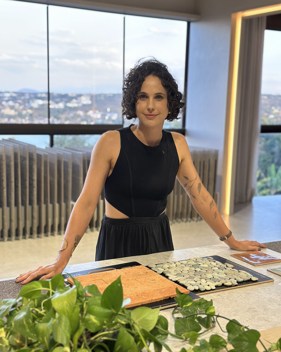 Arquiteta Aline Kreppel em pé à bancada, com amostras de materiais e revestimentos à sua frente